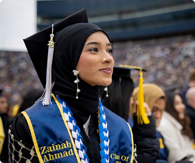 A student in cap and gown smiles during commencement