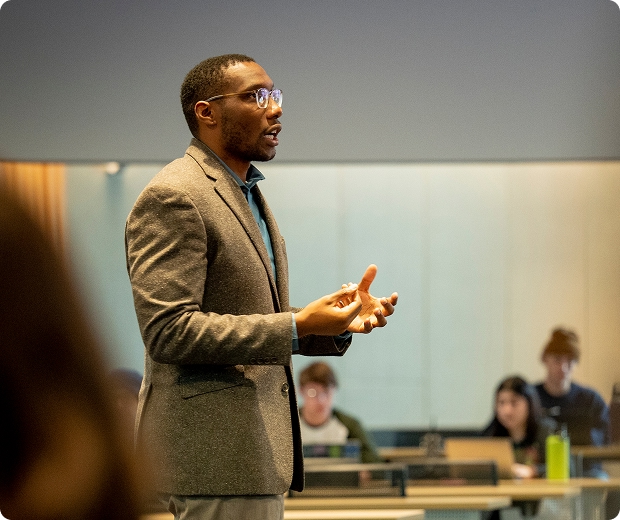 Faculty member teaching with students in the background