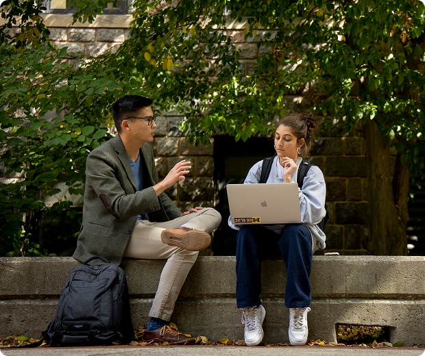 Faculty and student sit outside talking